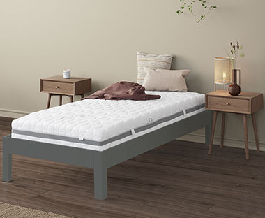Single gold mattress on a simple bedframe with bedside tables and decor