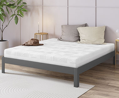Double gold mattress on a simple bedframe with bedside tables and decor